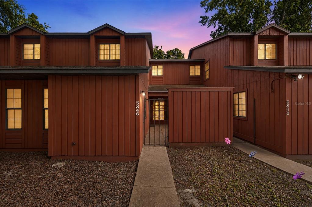 A two-story brown wood-sided building features a central gated walkway and multiple windows — 5846 SW 9TH PLACE, GAINESVILLE, FL
