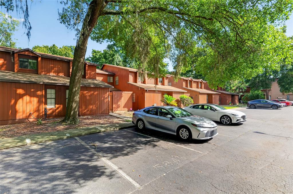 A row of brown wooden townhouses with a parking lot and trees in the foreground — 5846 SW 9TH PLACE, GAINESVILLE, FL