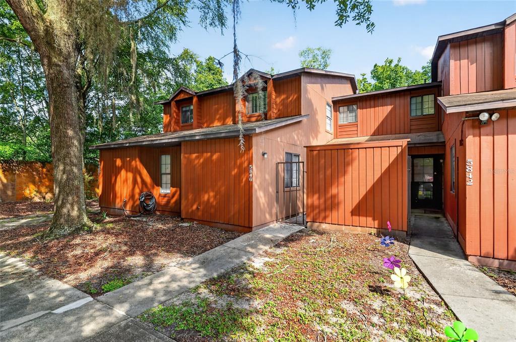A two-story townhouse exterior with brown vertical wood siding and a concrete walkway — 5846 SW 9TH PLACE, GAINESVILLE, FL