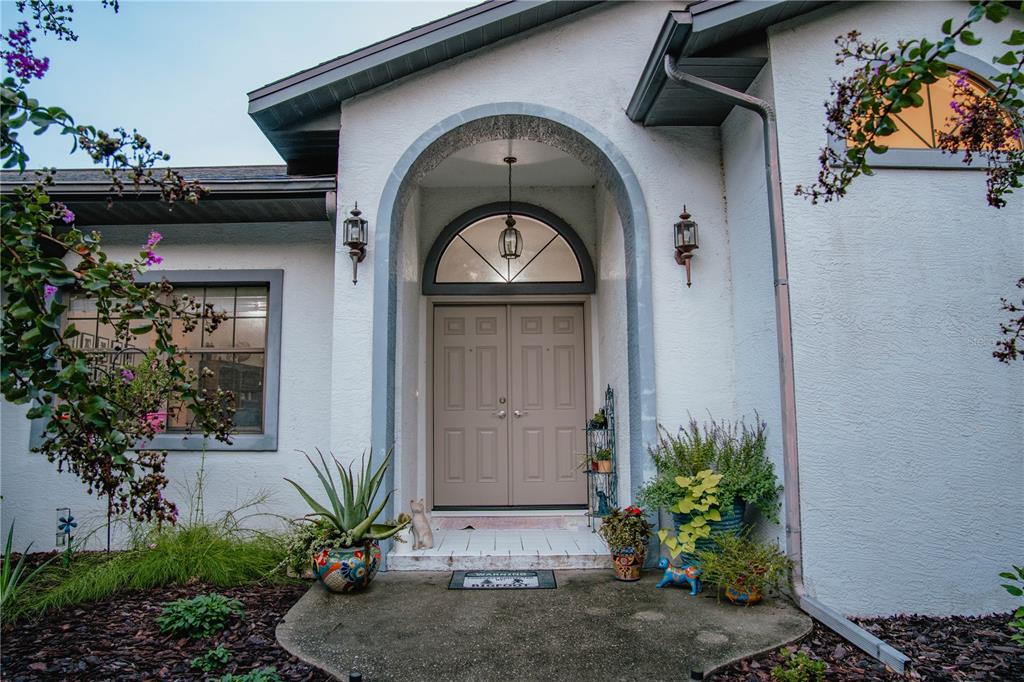 The exterior of a house features a double front door under an arched entryway — 12009 S DAFFODIL POINT, FLORAL CITY, FL