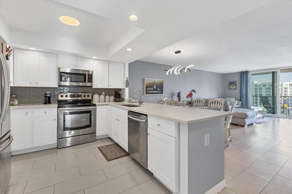 A modern kitchen with white cabinets and stainless steel appliances opens to a living area — 101 S GULFSTREAM AVENUE UNIT 15E, SARASOTA, FL