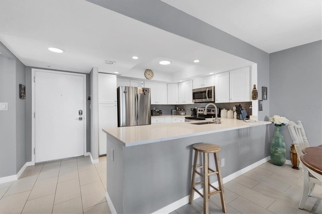 A kitchen features white cabinets, stainless steel appliances, a breakfast bar, and light-colored tile flooring — 101 S GULFSTREAM AVENUE UNIT 15E, SARASOTA, FL