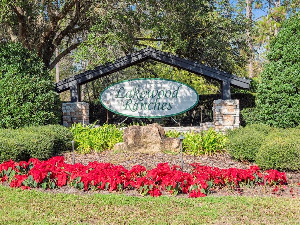 A sign for Lakewood Ranches sits behind a bed of red poinsettias and landscaping — 24250 DEEP SPRINGS LOOP, EUSTIS, FL