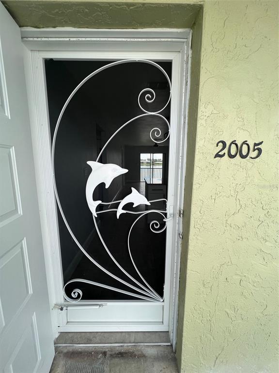 A white screen door with a decorative dolphin design is installed at the building entrance — 25225 RAMPART BOULEVARD UNIT 2005, PUNTA GORDA, FL