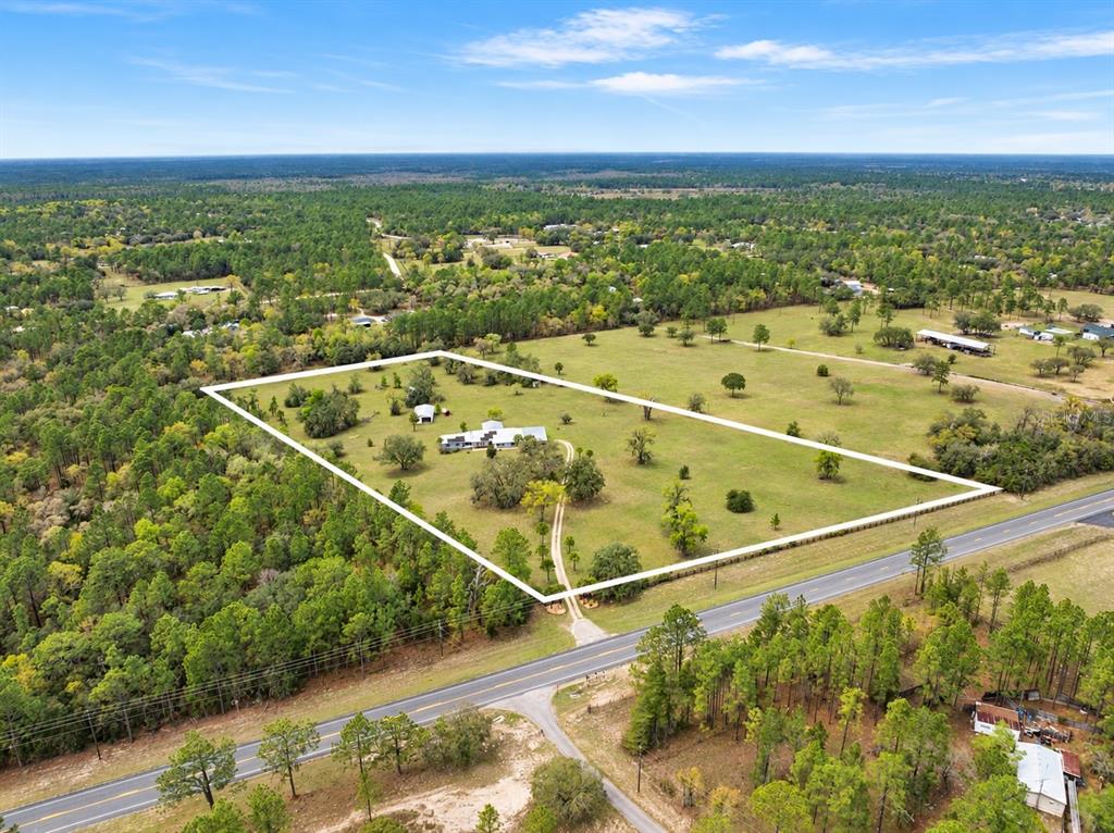 A single-story house with a metal roof and solar panels sits on a grassy lot — 7450 SE STATE ROAD 121, MORRISTON, FL