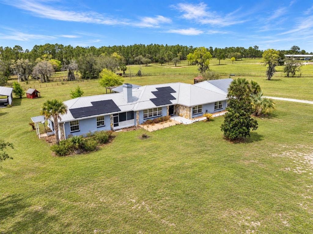 A living room features a stone fireplace, tile floors, a wooden coffee table, and windows — 7450 SE STATE ROAD 121, MORRISTON, FL