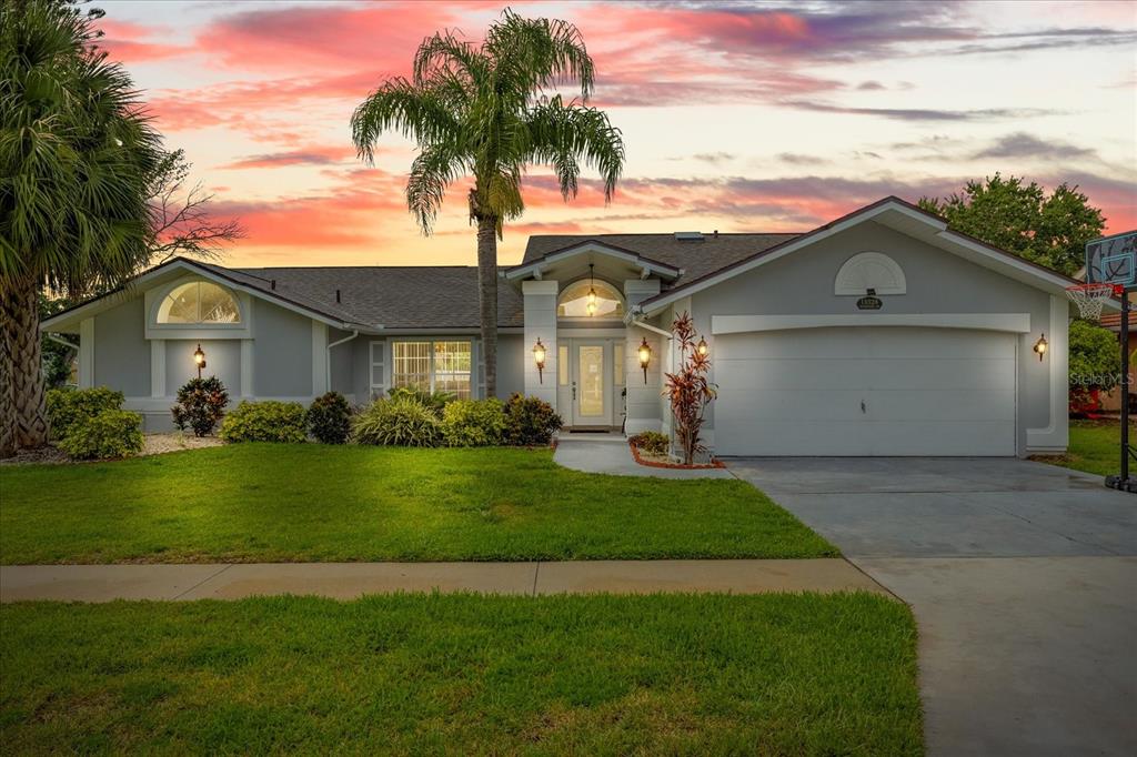 A single-story house with a gray exterior, a two-car garage, and a palm tree — 13528 WOODSIDE DRIVE, HUDSON, FL