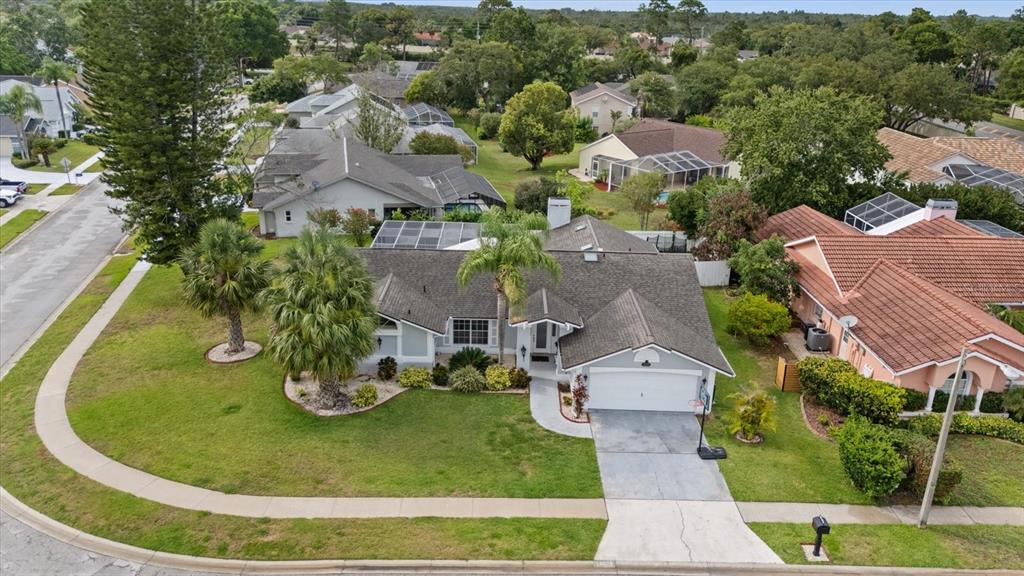 An aerial view shows a single-story house with a gray roof and a concrete driveway — 13528 WOODSIDE DRIVE, HUDSON, FL