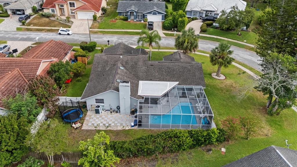 An aerial view shows a house with a screened-in pool, patio, and backyard trampoline — 13528 WOODSIDE DRIVE, HUDSON, FL