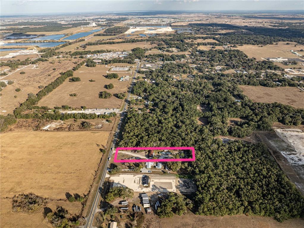 An aerial view shows a rectangular property outlined in pink amidst a rural, wooded landscape — 1859 E C 470, SUMTERVILLE, FL