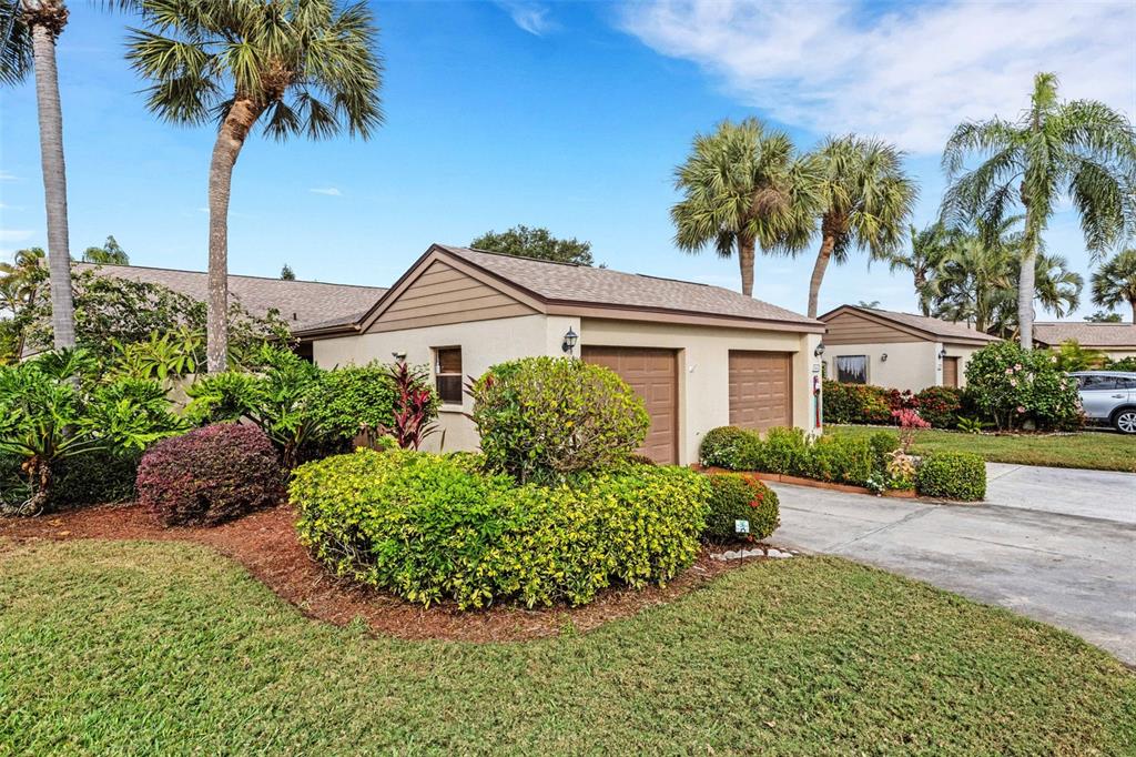 A beige house with a two-car garage and landscaped yard under a blue sky — 3441 BEEKMAN PLACE UNIT 40, SARASOTA, FL
