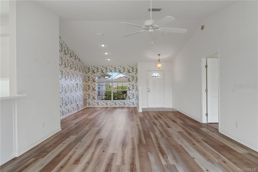 A living room with wood-look flooring, a vaulted ceiling, a ceiling fan, and floral wallpaper — 4589 N GRASS ISLAND TERRACE, HERNANDO, FL