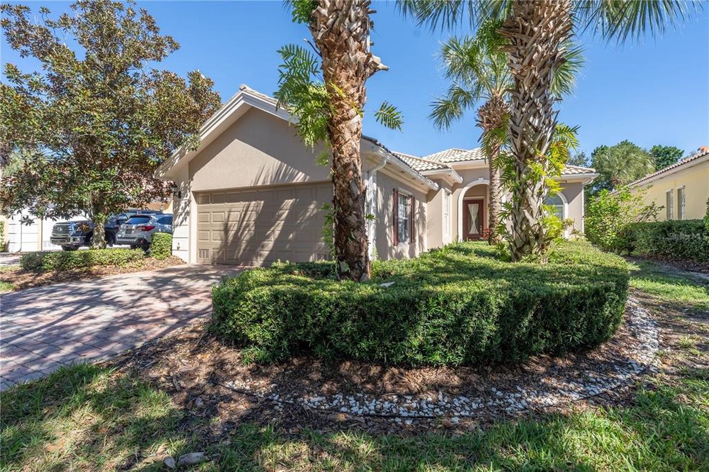 A single-story house with a tan stucco exterior, a two-car garage, and palm trees — 11731 EAGLE RAY LANE, ORLANDO, FL