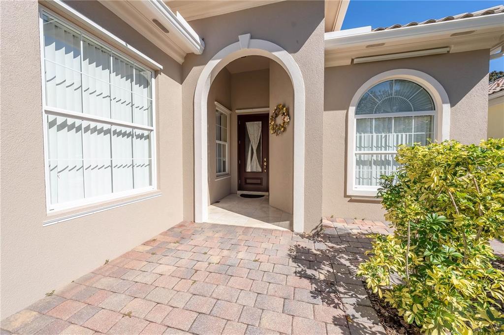 The front entrance features a paved walkway, a dark wood door, and arched architectural details — 11731 EAGLE RAY LANE, ORLANDO, FL