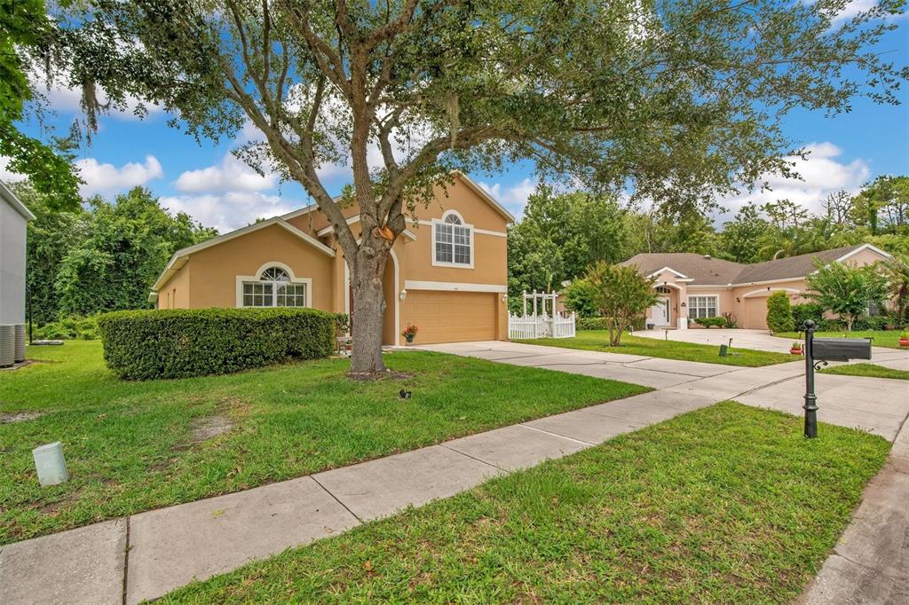 A two-story tan house with a front-facing garage and a concrete driveway — 469 CAREY WAY, ORLANDO, FL