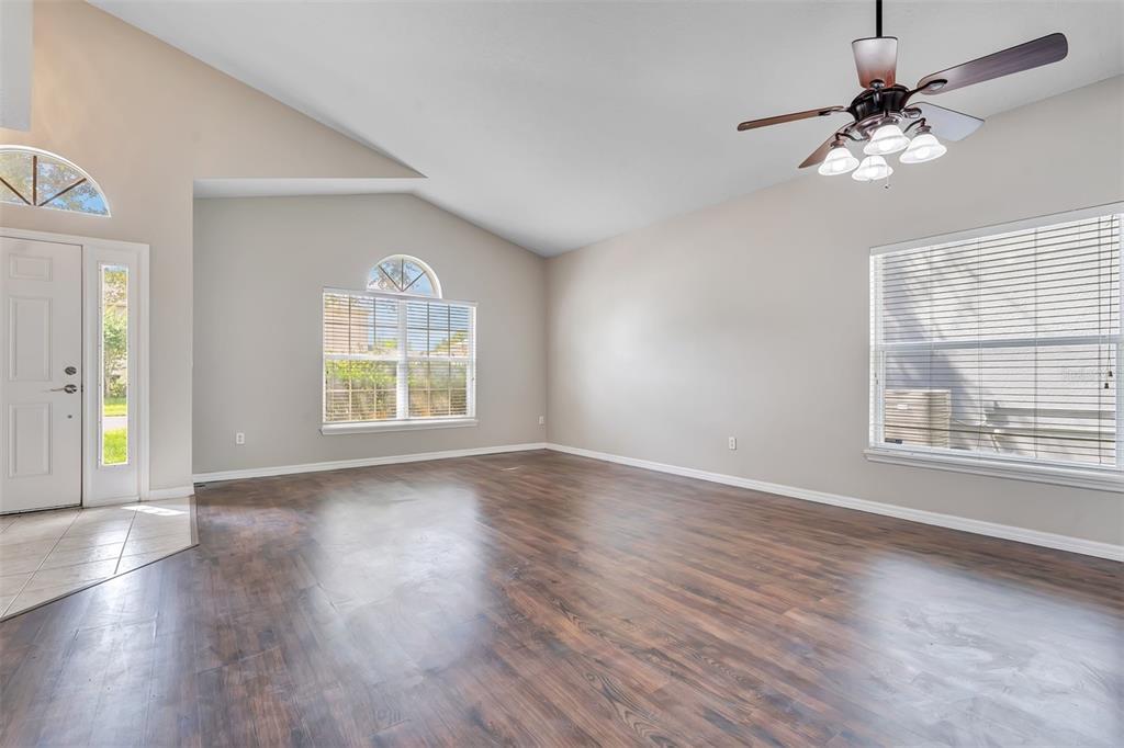 An empty living room features yellow walls, dark wood-look flooring, and a ceiling fan — 469 CAREY WAY, ORLANDO, FL