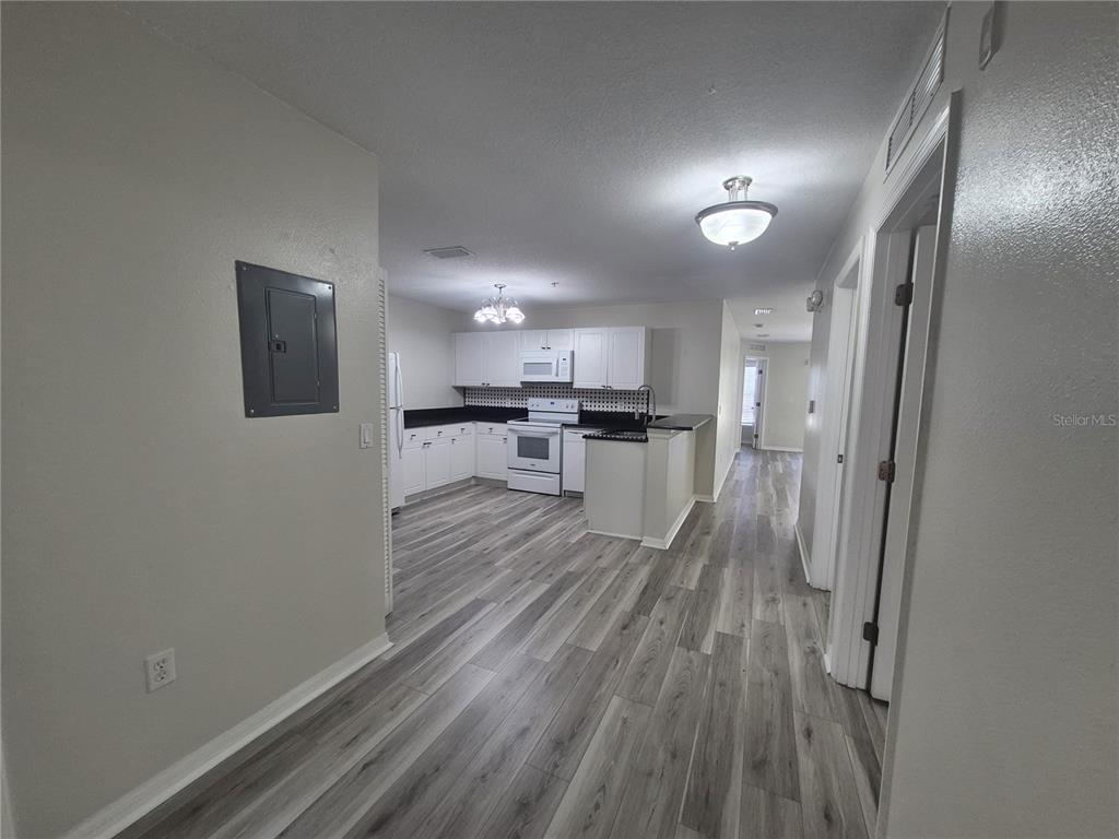 A kitchen features white cabinets, black countertops, a white refrigerator, and wood-look flooring — 2720 CLUB CORTILE CIRCLE UNIT A, KISSIMMEE, FL
