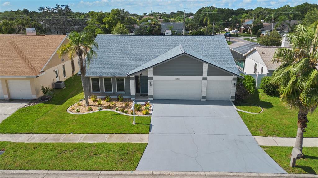 An aerial view of a single-story house with a gray roof, garage, and front yard — 12212 STEPPINGSTONE BOULEVARD, TAMPA, FL