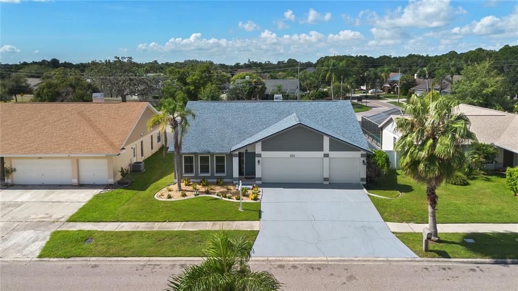 An aerial view of a single-story house with a gray roof, garage, and palm trees — 12212 STEPPINGSTONE BOULEVARD, TAMPA, FL