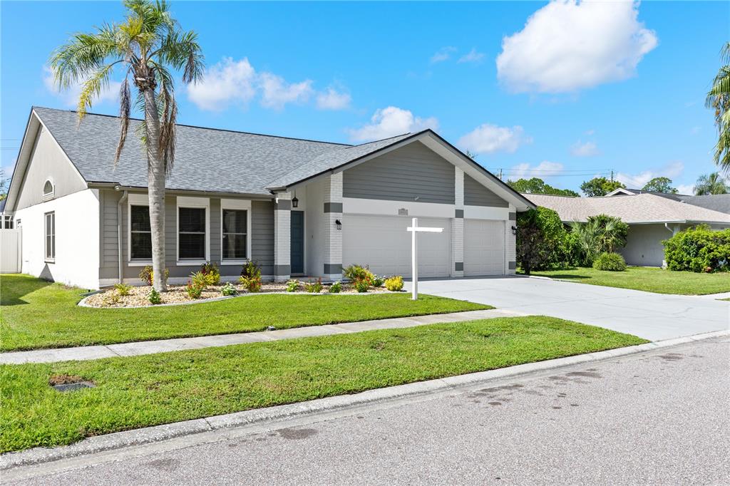 A single-story house with a two-car garage, gray siding, and a palm tree in front — 12212 STEPPINGSTONE BOULEVARD, TAMPA, FL