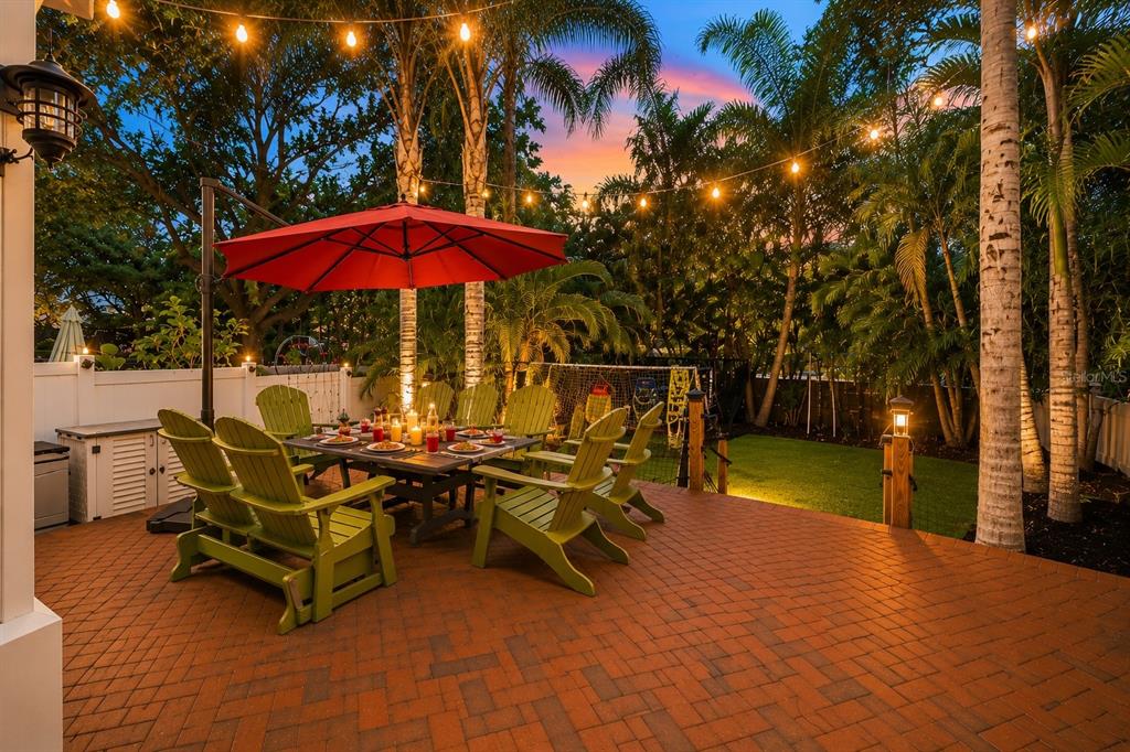 A patio with a dining table, umbrella, and outdoor kitchen area under a covered porch — 2869 BAYSHORE TRAILS DRIVE, TAMPA, FL