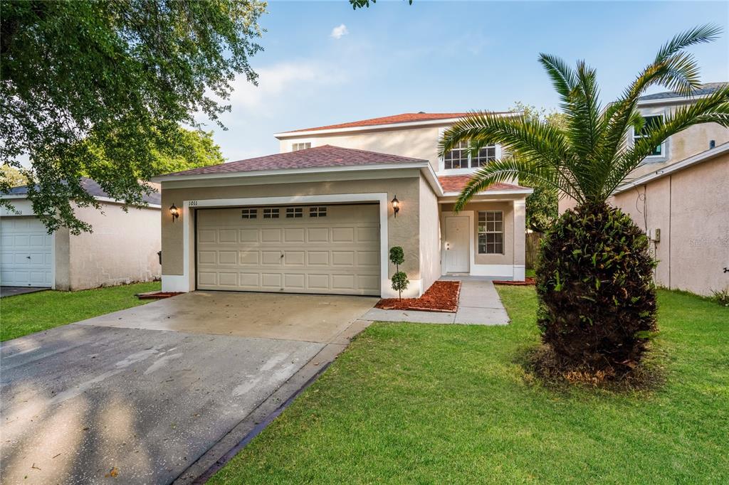 A two-story house with a beige stucco exterior, a two-car garage, and a palm tree — 1011 LAKE SHORE RANCH DRIVE, SEFFNER, FL
