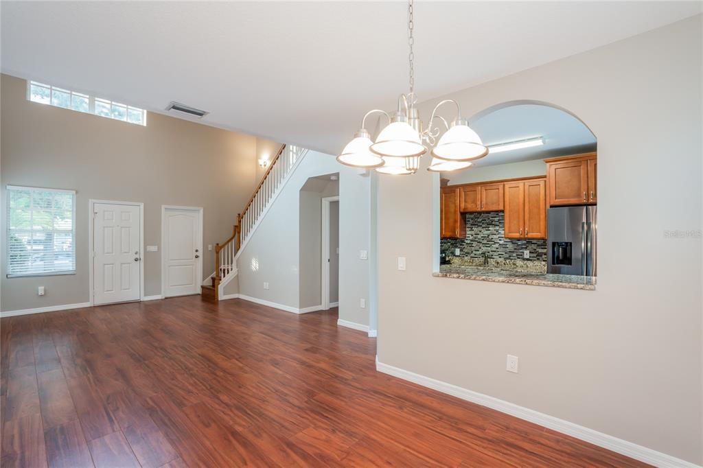 A living area with wood floors, a staircase, and an arched opening to the kitchen — 1011 LAKE SHORE RANCH DRIVE, SEFFNER, FL
