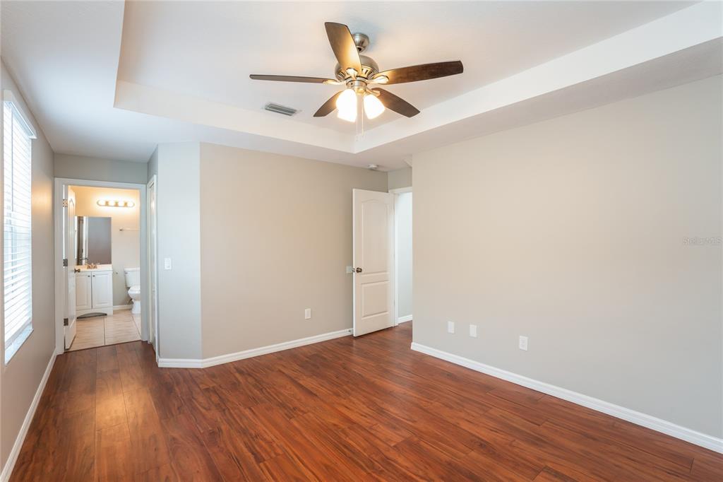 A bedroom with wood-look flooring, a ceiling fan, and an attached bathroom — 1011 LAKE SHORE RANCH DRIVE, SEFFNER, FL