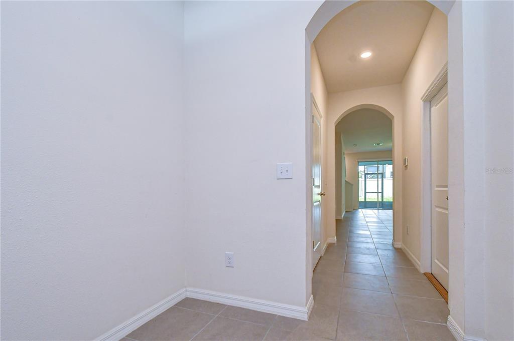 A hallway with arched entryways leads toward a sunlit room with a sliding glass door — 3326 PLEASANT WILLOW COURT, BRANDON, FL