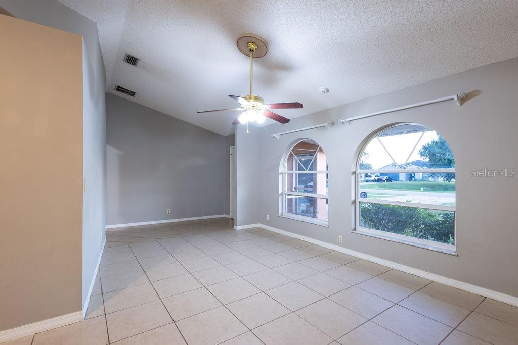 An empty room with vaulted ceilings, tile flooring, a ceiling fan, and two arched windows — 1570 S BISCAYNE DRIVE, NORTH PORT, FL