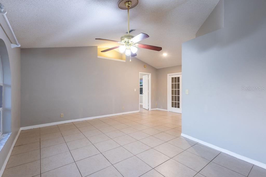 A living room with light gray walls, tile flooring, and a vaulted ceiling with a fan — 1570 S BISCAYNE DRIVE, NORTH PORT, FL