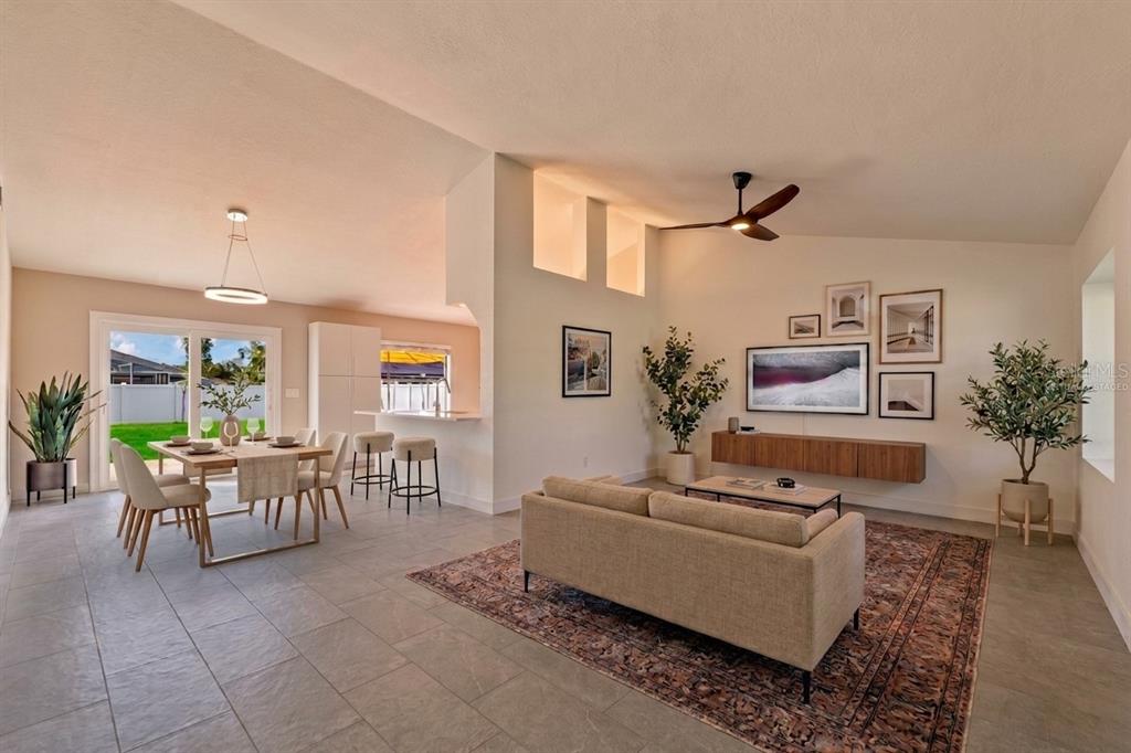 A bright open-concept living and dining area features tile flooring, a sofa, and sliding doors — 77 FREEPORT LANE, PALM COAST, FL