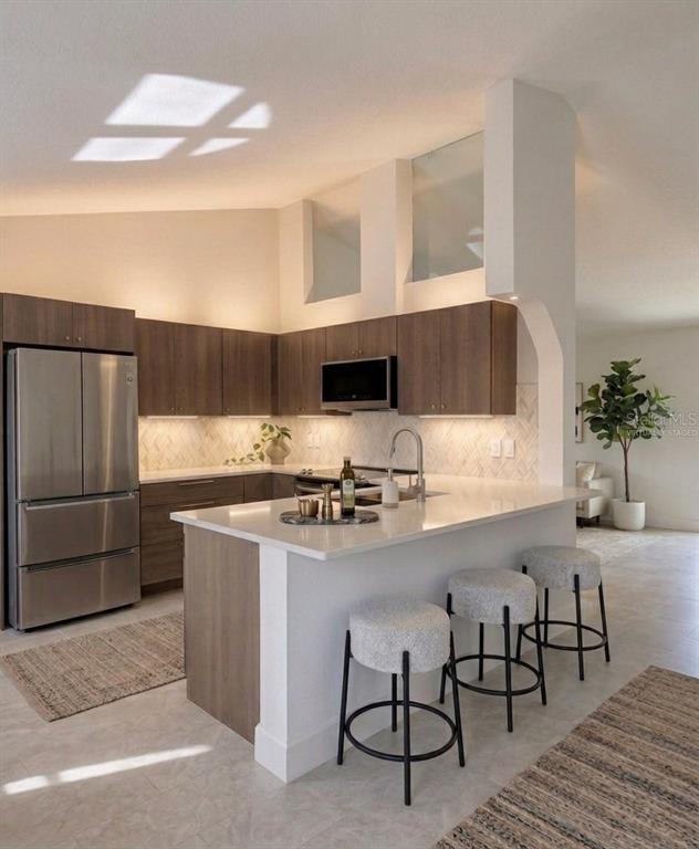 A modern kitchen features wood cabinets, white countertops, a breakfast bar, and three stools — 77 FREEPORT LANE, PALM COAST, FL