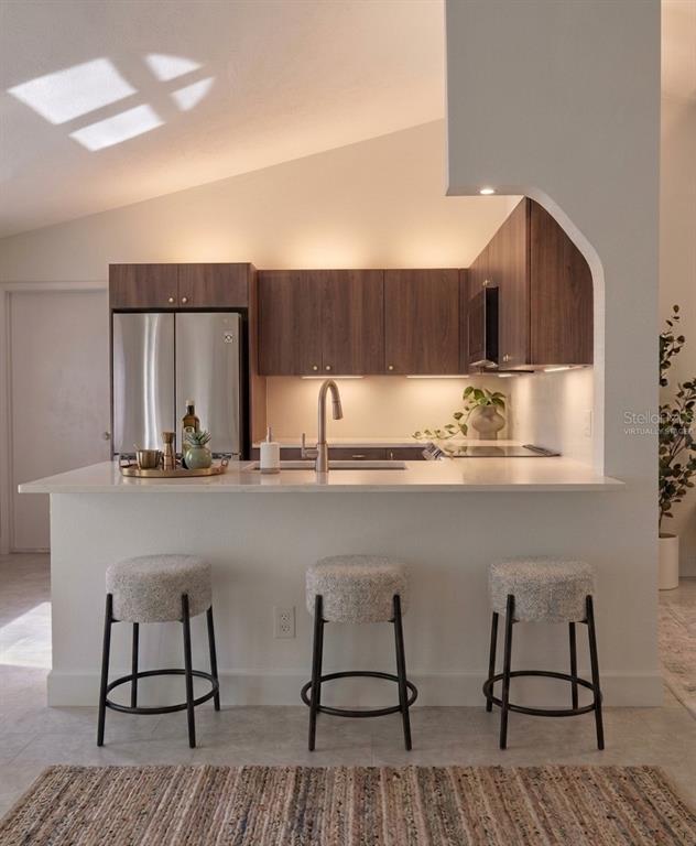 A kitchen with wood cabinets, stainless steel appliances, and a breakfast bar with three stools — 77 FREEPORT LANE, PALM COAST, FL