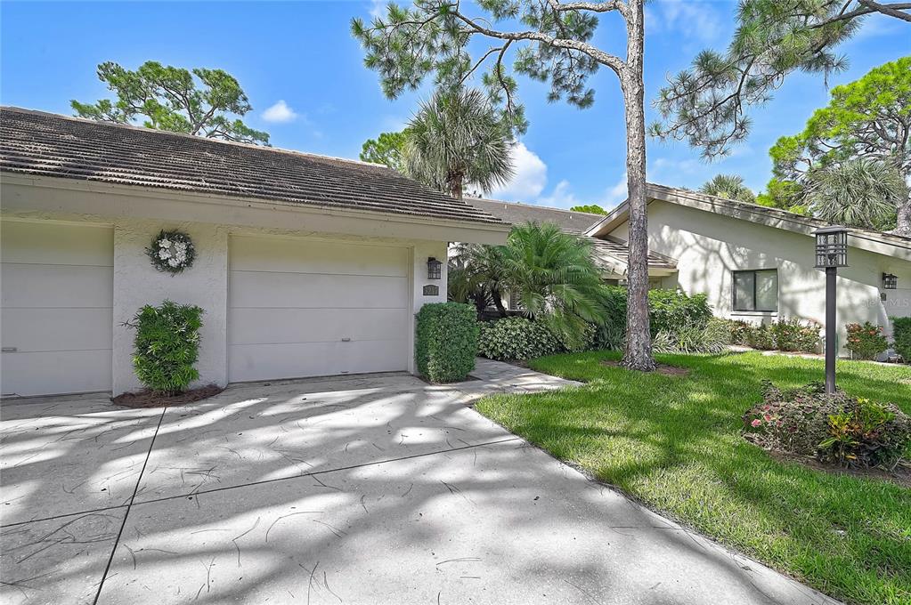 A single-story residential building with a two-car garage, concrete driveway, and landscaped front yard — 3217 SANDLEHEATH UNIT 45, SARASOTA, FL