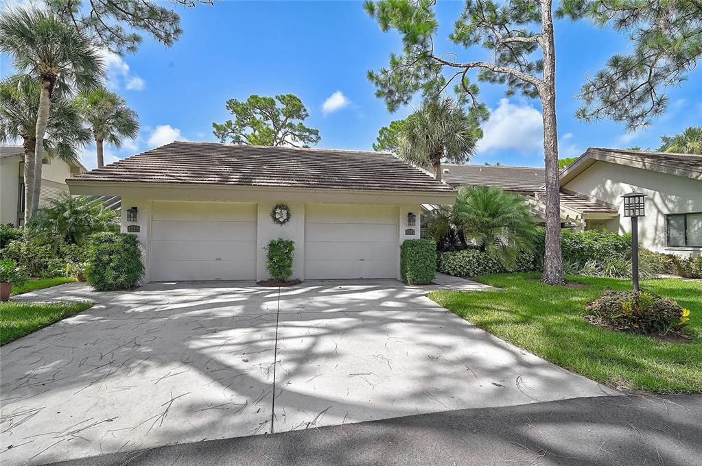 A two-car garage with a concrete driveway sits in front of a single-story residential building — 3217 SANDLEHEATH UNIT 45, SARASOTA, FL