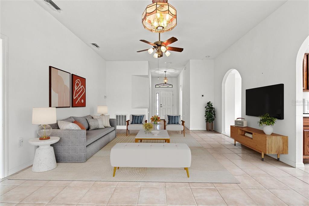 A bright living room features a gray sofa, white bench, and tile flooring — 347 ROYAL PALM DR, DAVENPORT, FL