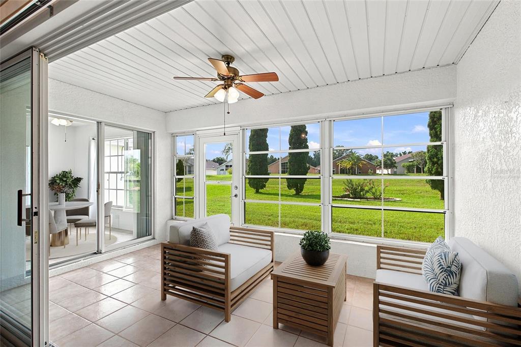 A sunroom features tile flooring, a ceiling fan, and large windows overlooking a grassy yard — 347 ROYAL PALM DR, DAVENPORT, FL