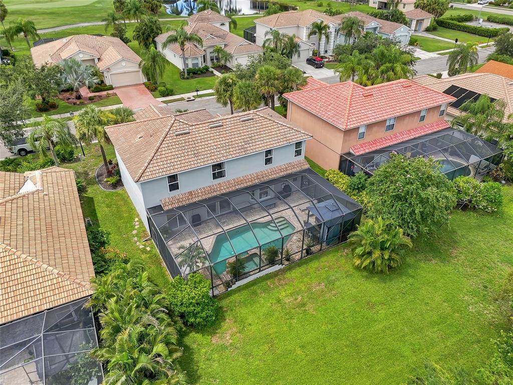 An aerial view shows a two-story house with a screened-in pool and backyard lawn — 227 HERITAGE ISLES WAY, BRADENTON, FL