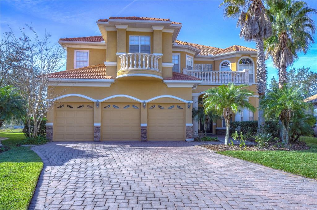 A two-story house with a three-car garage, a balcony, and a paved driveway — 10602 CAYMAN ISLE COURT, TAMPA, FL