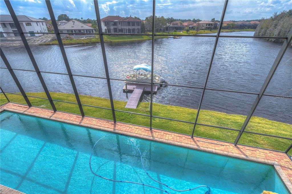 A screened-in pool overlooks a lake with a private dock and a pontoon boat — 10602 CAYMAN ISLE COURT, TAMPA, FL