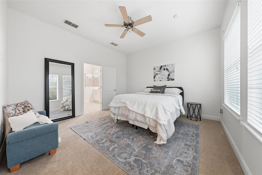 An open-concept kitchen and living area features light blue walls, tile flooring, and white cabinetry — 16716 ABBEY HILL COURT, CLERMONT, FL