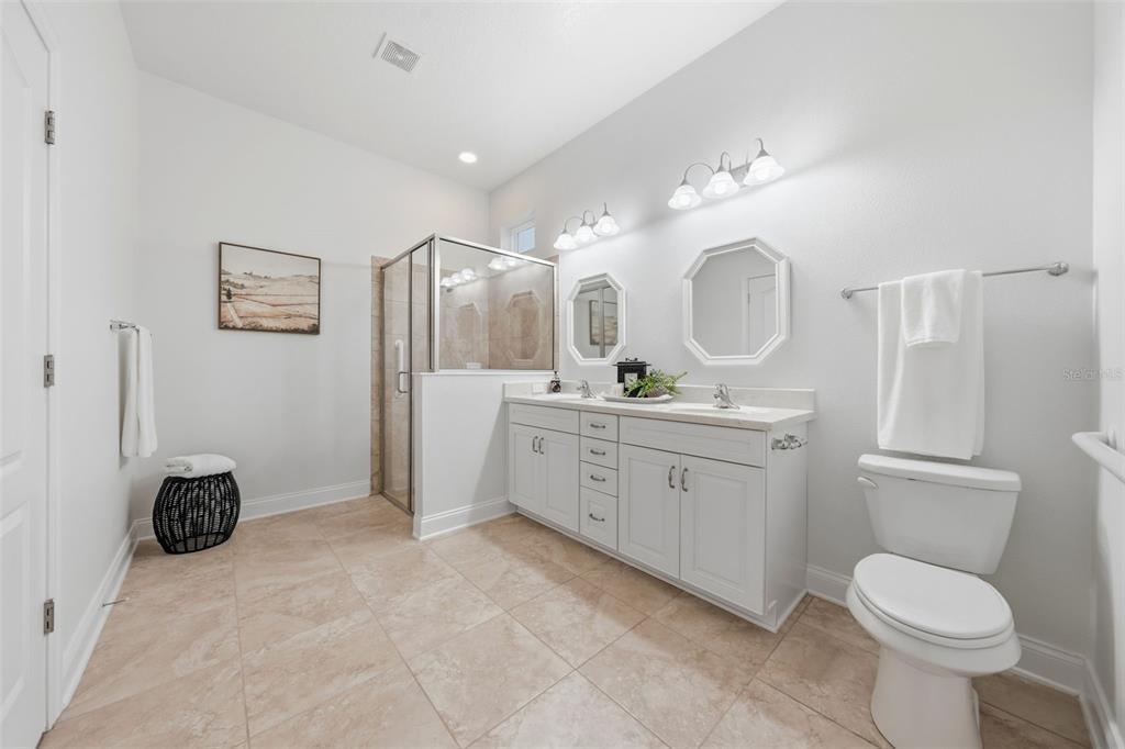 A bedroom features a bed, a blue armchair, a floor mirror, and a ceiling fan — 16716 ABBEY HILL COURT, CLERMONT, FL