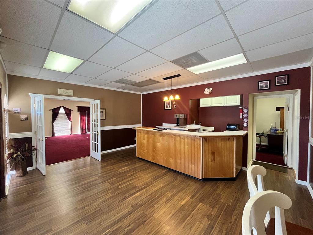 A room features wood-look flooring, a wooden bar counter, and a doorway to a red-carpeted room — 1165 1ST STREET S UNIT 1165, WINTER HAVEN, FL