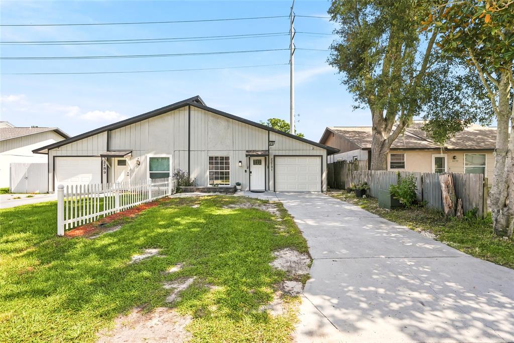 A duplex with two garages, a white picket fence, and a concrete driveway — 22791 PENNY LOOP, LAND O LAKES, FL