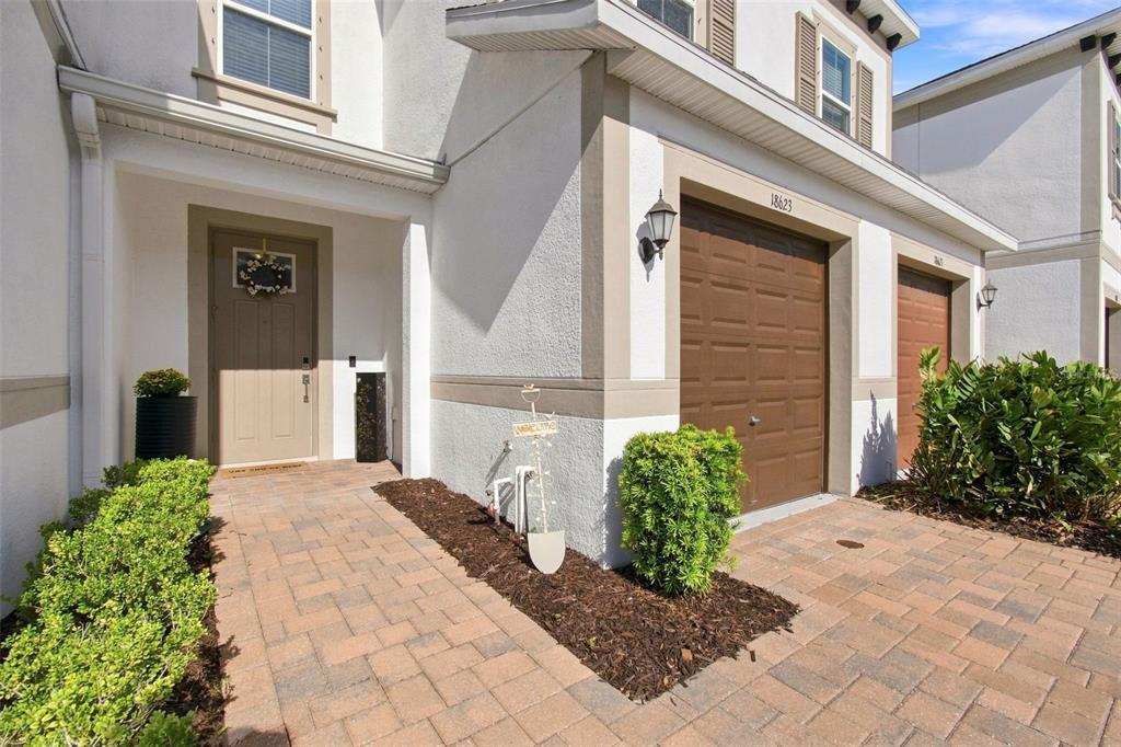 A paved walkway leads to the front door and garage of a two-story stucco townhouse — 18623 NOBLE CASPIAN DRIVE, LUTZ, FL