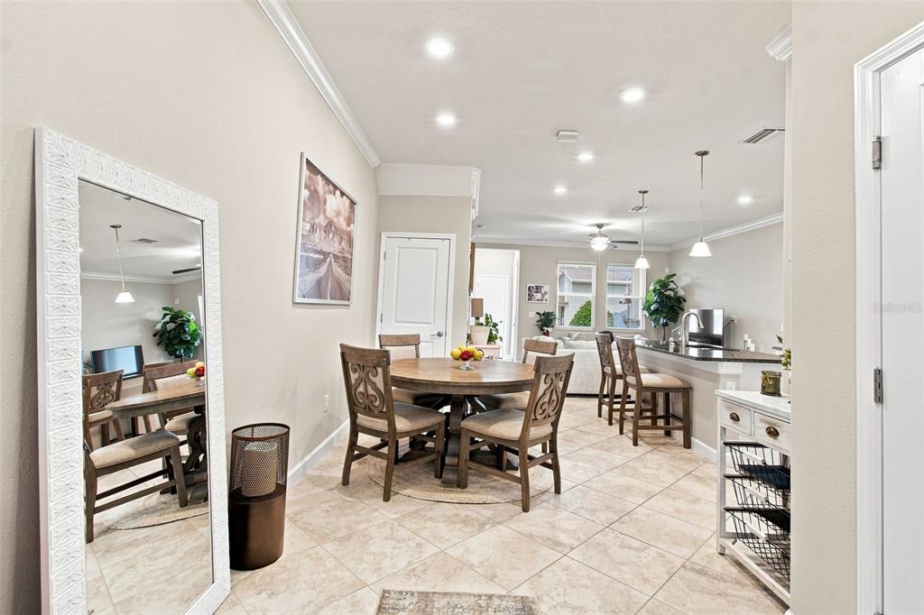 A dining area with a round wooden table and chairs sits adjacent to a kitchen island — 18623 NOBLE CASPIAN DRIVE, LUTZ, FL