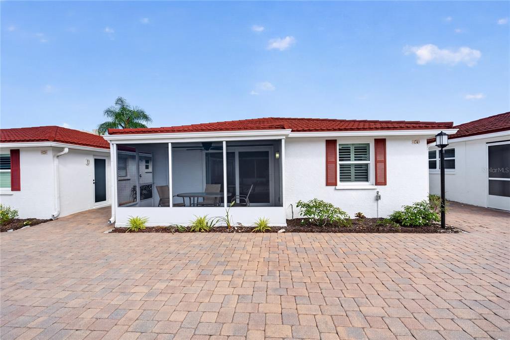 A white house with a red tile roof features a screened-in patio and brick pavers — 6154 MIDNIGHT PASS ROAD UNIT VILLA4C, SARASOTA, FL