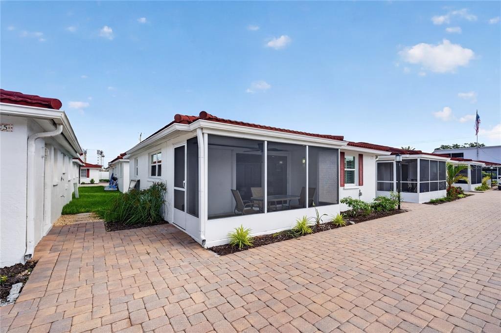 A white villa with a screened-in porch and a red tile roof sits on pavers — 6154 MIDNIGHT PASS ROAD UNIT VILLA4C, SARASOTA, FL