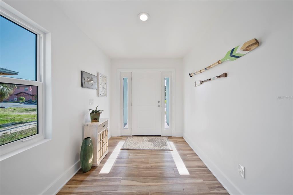 A bright entryway features wood-look tile flooring, white walls, and decorative oars on the wall — 15564 BERTRAM DRIVE, HUDSON, FL